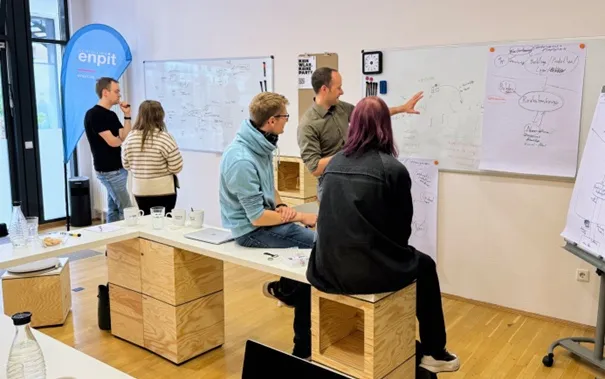 Softwarearchitekt:innen und Softwareentwickler:innen von enpit stehen vor einem Whiteboard und betrachten ein Softwarearchitektur Diagramm