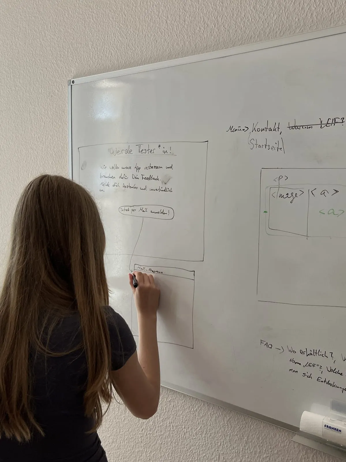 Mädchen steht während Ihres Schülerpraktikums bei enpit vor einem Whiteboard und zeichnet Wireframes für eine Webseite