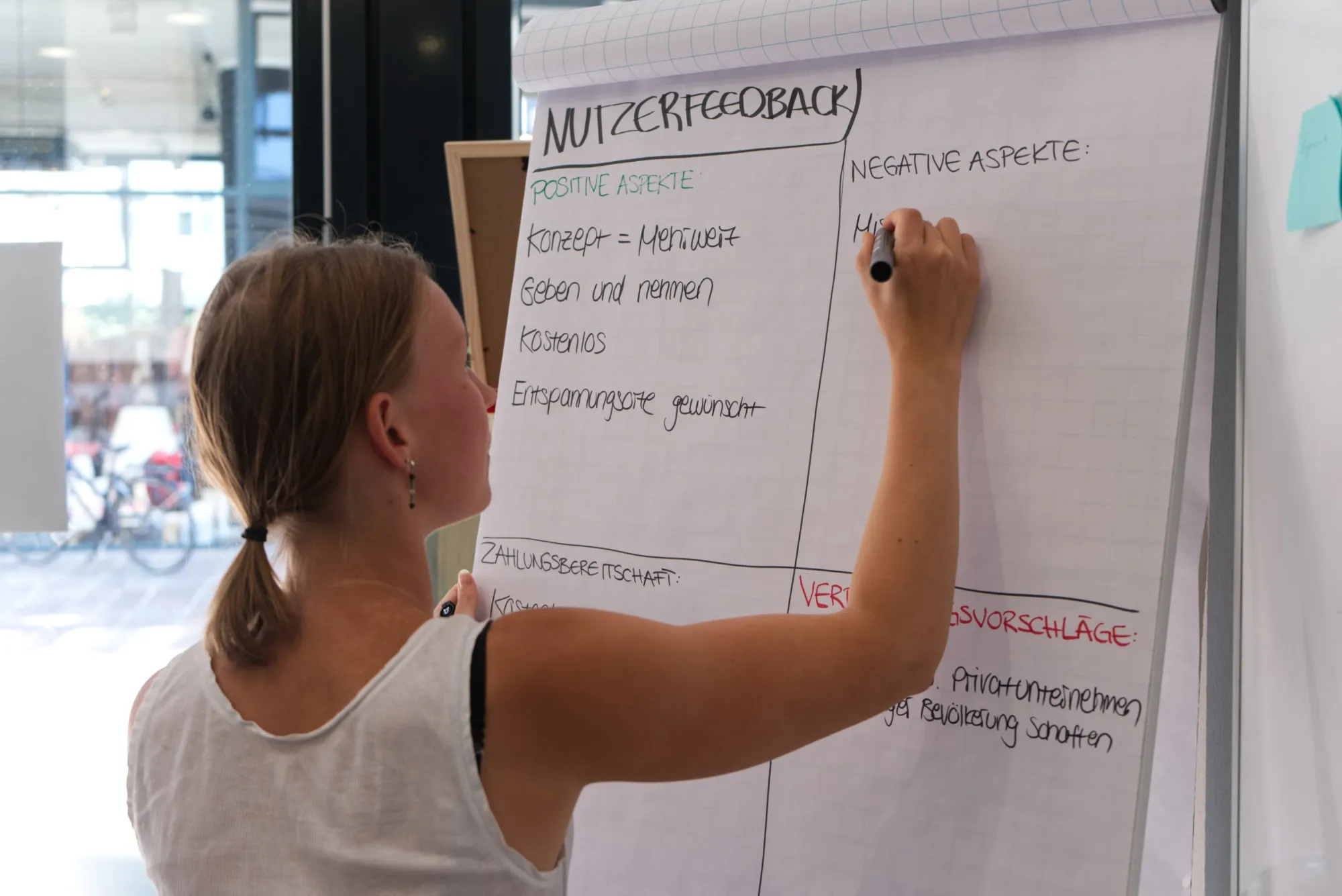 Studentin hält Feedback aus der User Research Übung am Flipchart fest